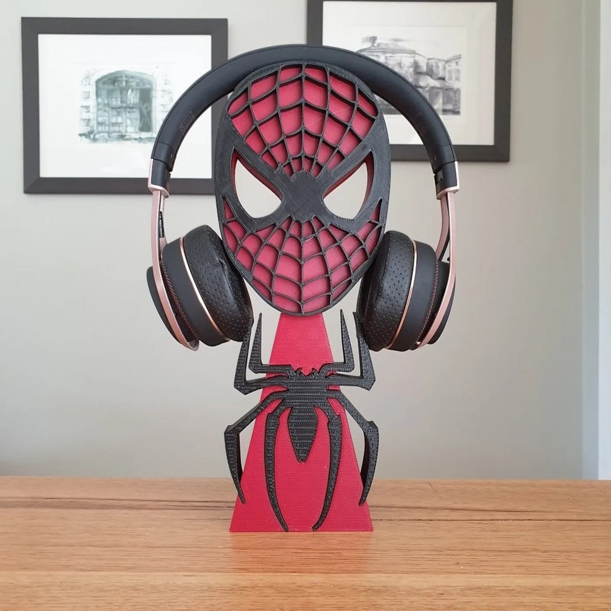 Magicland 3D Spiderman mask headphone stand in black and red with a spider design. Holds rose gold headphones.