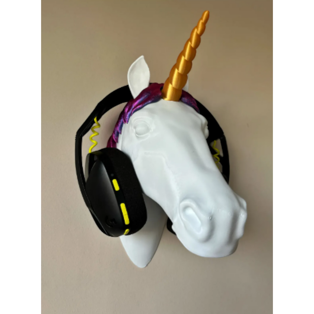 Magicland 3D white unicorn head headphone stand with gold horn and purple mane, holding black headphones.