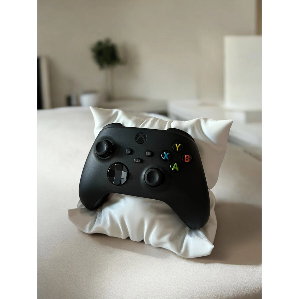 Magicland 3D decorative pillow stand holding a black Xbox controller on a light-colored surface.