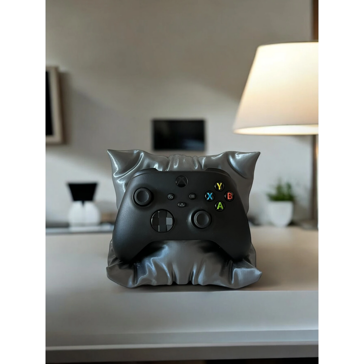 Magicland 3D grey pillow-shaped stand holding a black Xbox controller on a desk.