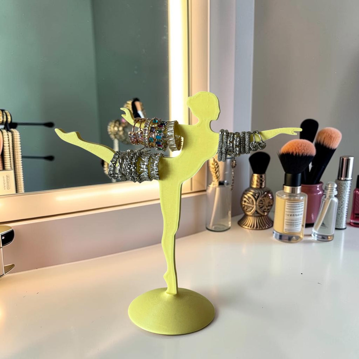 Magicland 3D yellow 3D printed ballerina jewelry stand holding bracelets and rings.