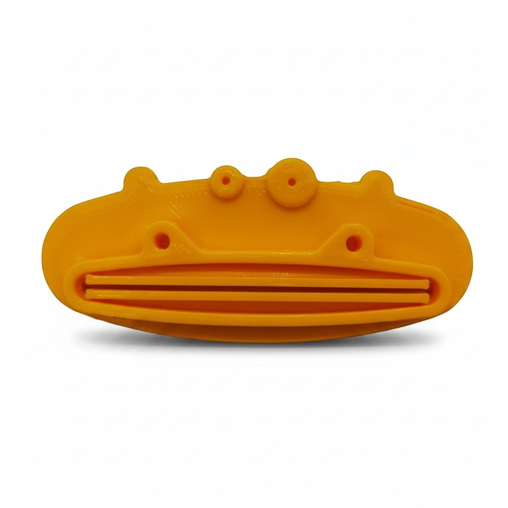 Magicland 3D yellow pig-shaped plastic toothpaste squeezer with slots for dispensing toothpaste.